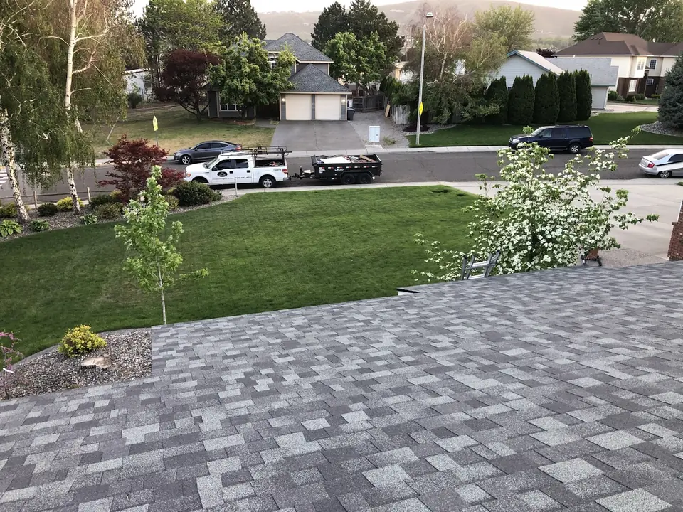 Newly installed gray shingle roof seen from the ridge, looking down over a residential street